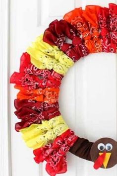 a paper plate turkey wreath on a white door with red, yellow and orange ruffles