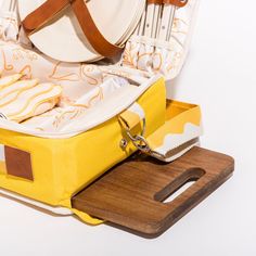 an open suitcase sitting on top of a wooden cutting board next to a white plate