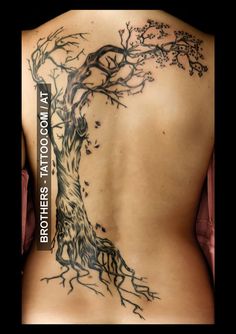 a woman's back with a tree tattoo on it