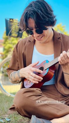 a woman sitting on the ground playing an ukulele with her hands and fingers