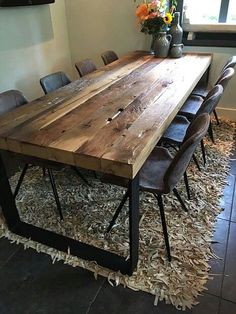 a dining room table made out of wood and metal legs with chairs around it, in front of a window