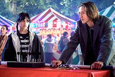 two people standing at a table in front of a tent with tents and booths behind them