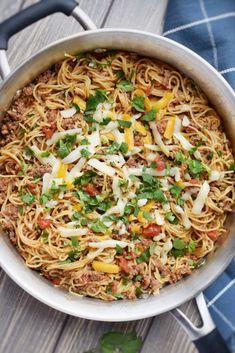 a large pot filled with noodles and meat on top of a wooden table next to a blue towel