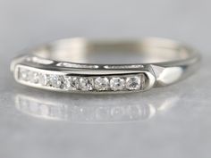 a white gold wedding ring with five diamonds on it's sides and the band is slightly curved