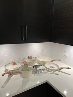 a kitchen counter with pots and pans on it's side, in front of black cabinets