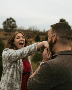 a man and woman standing next to each other with their arms around one another as they laugh