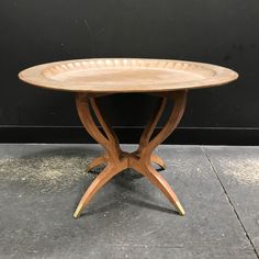 a round wooden table with two legs and a circular tray on the top that is shaped like an x