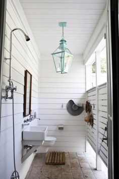 a bathroom with white walls and wood flooring next to a light hanging from the ceiling