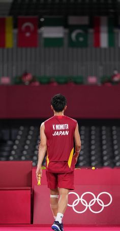 a man is walking on the court in front of an olympic sign