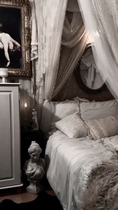 a white bed sitting next to a night stand with a painting on top of it