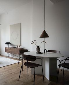 a dining room table with chairs and a vase on it