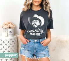 a woman standing in front of a couch wearing a black shirt with the words country malone on it