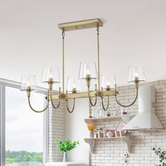 a chandelier hanging from a ceiling in a kitchen with brick wall and windows