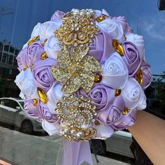 a bridal bouquet is being held in front of a window by someone's hand