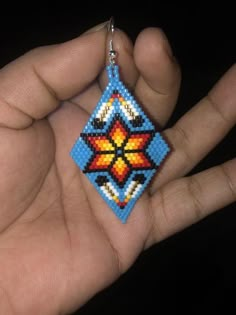 a hand holding a beaded square shaped keychain in it's palm