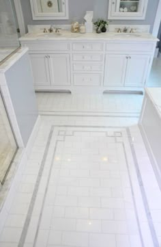 a white bathroom with two sinks, mirrors and tile flooring in the shower area