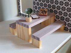 a small wooden bench sitting on top of a white counter next to a potted plant