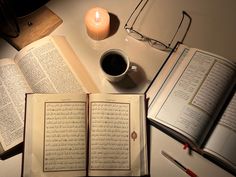 an open book sitting on top of a table next to a cup of coffee and glasses