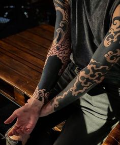 a man with tattoos on his arm sitting at a table