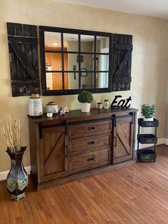 a wooden dresser sitting on top of a hard wood floor next to a wall mounted mirror