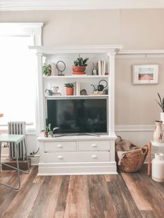 a living room filled with furniture and a flat screen tv on top of a white entertainment center