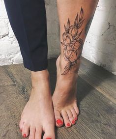 a woman's foot with a flower tattoo on her left leg and red nail polish