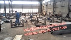 workers are working in an industrial factory with steel beams and frames on the floor, surrounded by other metal structures