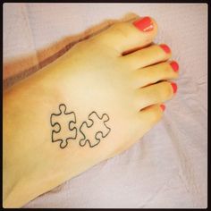 a woman's foot with a puzzle piece tattoo on it