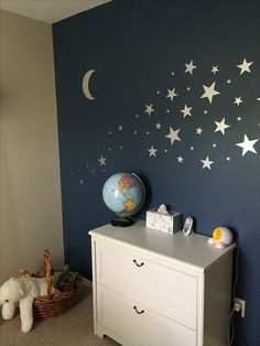 a white dresser sitting next to a wall with stars on it