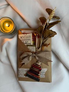 a candle and some books are on a bed next to a paper bag that has been wrapped in burlap