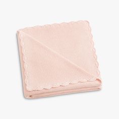 a pink blanket folded on top of a white surface with a scalloped edge