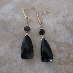 Onyx is a classic, timeless stone that lasts for decades. The faceted stones for these black post earrings are versatile for dressing up or down. You can wear these earrings almost anywhere, day or night. *Black onyx triangle-shaped stone: measures .75 inch by .4 inch *Accents: Black Swarovski crystals *18k gold-plated, sterling silver posts *Approximate length of earrings: 1.8 inches Formal Onyx Gemstone Earrings, Classic Onyx Jewelry For Party, Classic Black Earrings For Formal Occasions, Classic Onyx Earrings For Evening, Black Faceted Teardrop Jewelry, Formal Pierced Onyx Earrings, Faceted Drop Earrings For Evening, Onyx Earrings For Evening, Classic Black Diamond Earrings For Gift