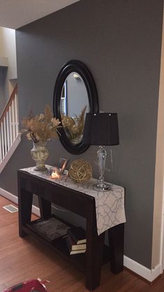 a living room with a table, mirror and vases on the side walk way