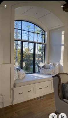 a window seat in front of a large window with lots of pillows on top of it