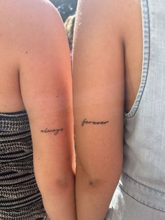 two people with matching tattoos on their arms, one is holding the other's arm