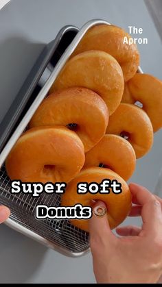 a person holding a metal tray with donuts on it and the words super soft donuts above them