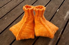 two orange socks sitting on top of a wooden table