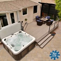 a hot tub sitting on top of a wooden deck next to a patio with chairs