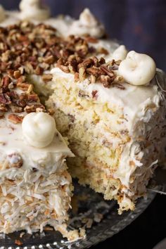 a cake with white frosting and pecans on top is cut in half to show the inside