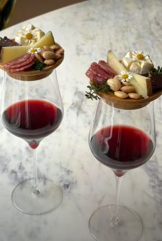 two wine glasses filled with different types of food on top of a marble countertop