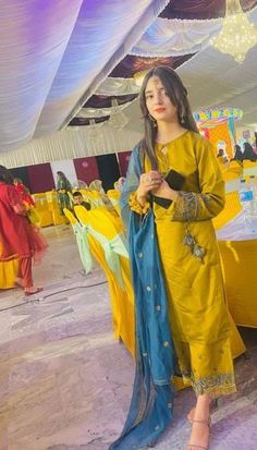 a woman standing next to a table covered in yellow and blue cloths