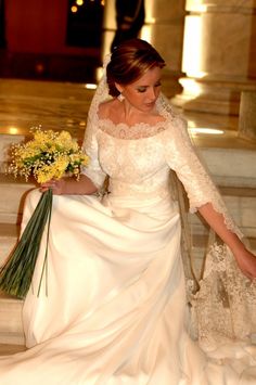 a woman in a wedding dress is walking down the stairs with flowers on her hand