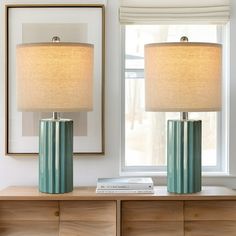 two lamps sitting on top of a dresser next to a window