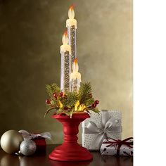 a red candle holder with lit candles and christmas decorations