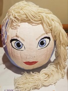 a paper mache doll with blonde hair and blue eyes sitting on top of a table