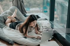 a woman laying on her stomach using a laptop computer while lying on the floor in front of a window