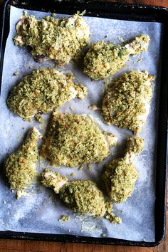 several pieces of chicken sitting on top of a baking pan covered in herbs and seasoning