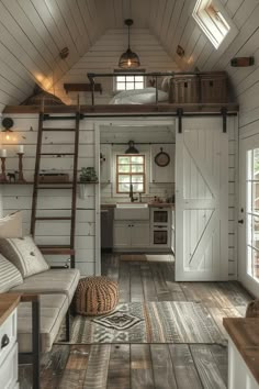 the interior of a tiny cabin with wood flooring and white walls, wooden stairs leading up to an open kitchen area