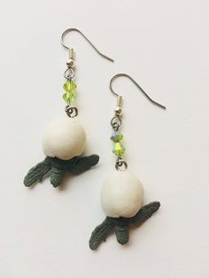 the earrings are made out of clay and glass beads with green leaves attached to them