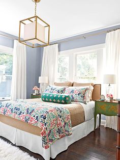 a bedroom with blue walls, white curtains and a large bed in the center of the room